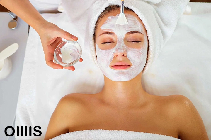 مراقبت از پوست در هر سنی،‌ یک خانم که روی تخت کلینیک خوابیده و در حال فیشیال کردن پوست صورت خود است و حوله سفید به تن کرده